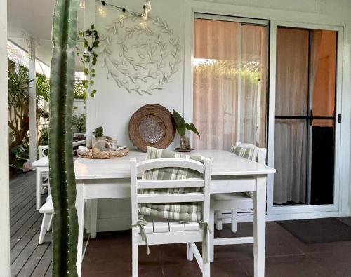a white dining table and chairs on a porch at The White Cottage Byron Bay in Suffolk Park