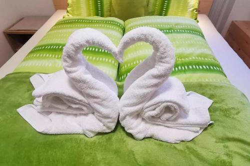 Dos toallas en una cama verde con dos cisnes en Bertollhof en Silandro