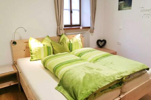 Una cama con sábanas verdes y almohadas. en Bertollhof en Silandro