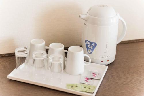a tray with cups and a tea kettle on a table at Daiwa Roynet Hotel Hakata-Gion in Fukuoka