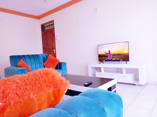 sala de estar con 2 sillas azules y TV en Bliss homestay apartment with swimming pool en Mtwapa