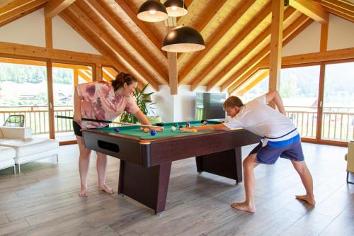 a man and a woman playing a game of billiard at Seehaus Winkler in Weissensee