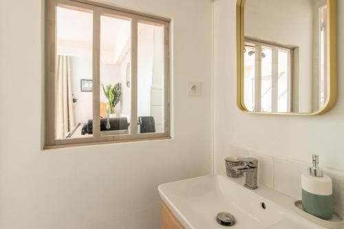 La salle de bains est pourvue d'un lavabo et d'un miroir. dans l'établissement Charming Apartment in the Heart of Versailles, à Versailles