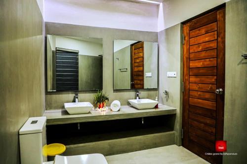 a bathroom with two sinks and two mirrors at Chillies Grand by Lathpandura, Polonnaruwa in Polonnaruwa
