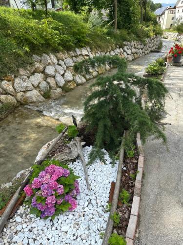 a garden with flowers and a stone wall at Hiša Srečo in Begunje na Gorenjskem