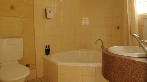 a bathroom with a tub and a toilet and a sink at Portside Motel in Port Campbell