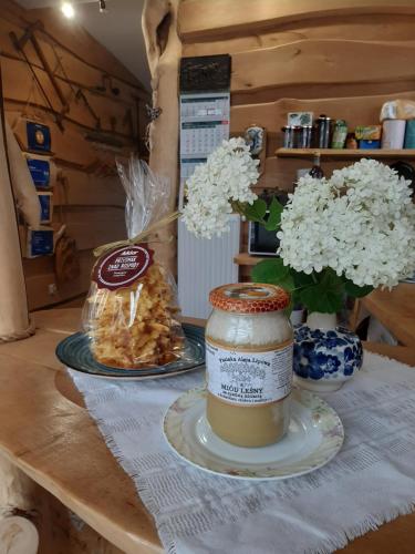 Una mesa con un frasco de miel y flores. en Olszynowy Zakątek -Mała magia en Augustów