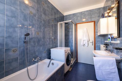 bagno piastrellato blu con vasca e lavandino di Stay'n Go Appartment a Bolzano