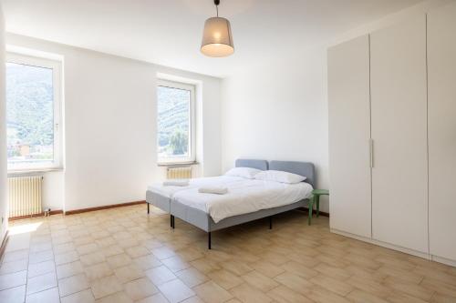 un letto in una camera bianca con due finestre di Stay'n Go Appartment a Bolzano