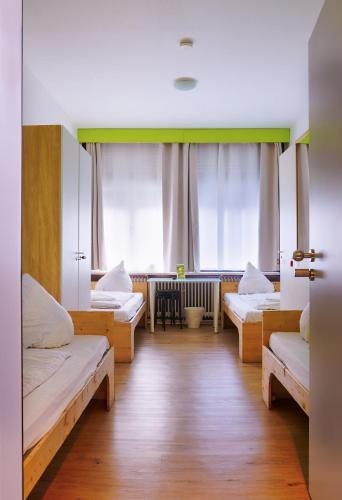 a room with three beds and a table at Hostel Gästehaus Kaiserpassage- Ihr Cityhostel in Karlsruhe