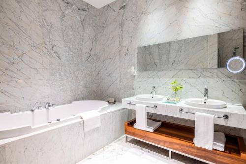 a white bathroom with two sinks and a tub at Tomtom Suites in Istanbul