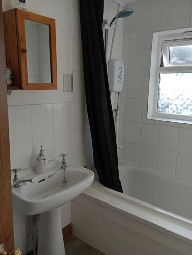 y baño con lavabo y bañera con cortina de ducha. en Bellevue cottage en Wicken
