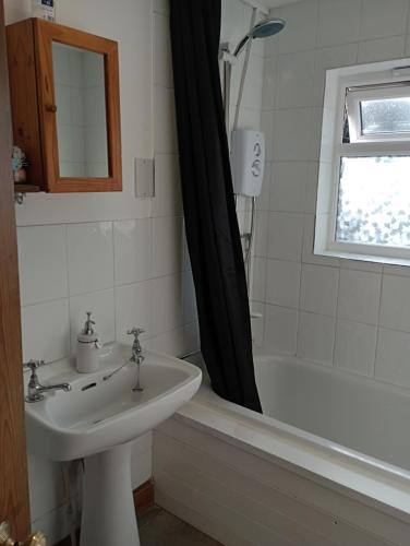 a bathroom with a sink and a bath tub with a shower curtain at Bellevue cottage in Wicken