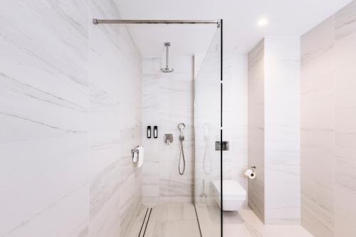 uma casa de banho branca com um chuveiro e um WC. em Grand Ascot Hotel em Cracóvia