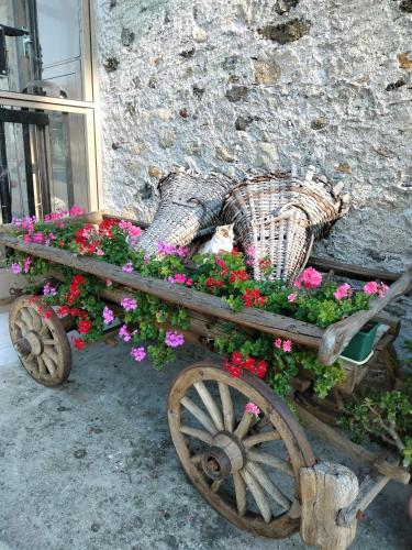 a wooden cart filled with flowers next to a building at Il posto al sole in Teglio