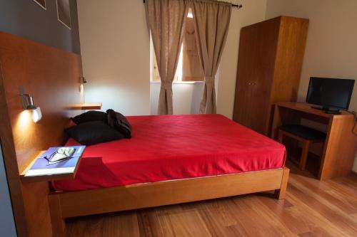 a bedroom with a red bed with a desk and a television at Pico da Saudade in Prainha de Baixo