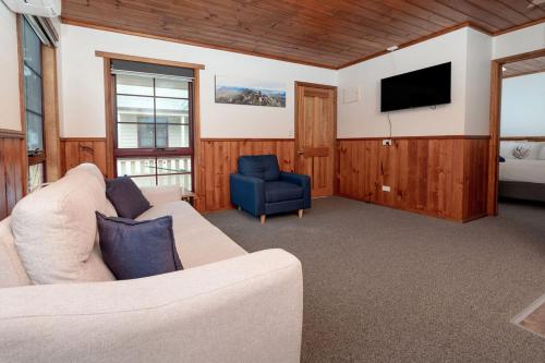 sala de estar con sofá y TV en Kitty's Cottages - Managed by BIG4 Strahan Holiday Retreat, en Strahan