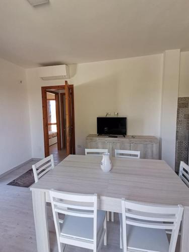 a white dining room table with white chairs and a television at Santa Luria Casa dolce Casa in Santa Luria