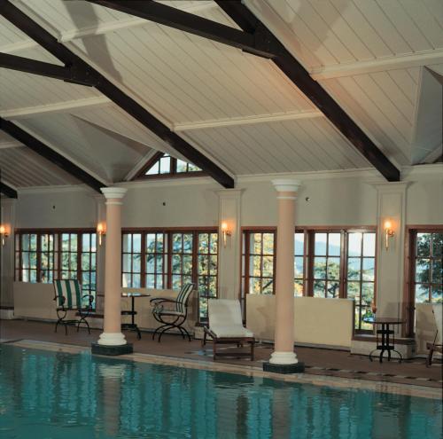 uma piscina interior com cadeiras, mesas e janelas em The Oberoi Cecil em Shimla