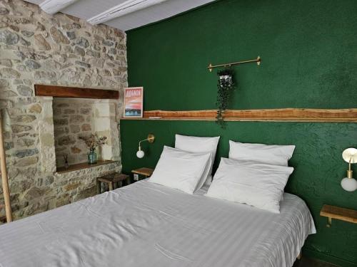 een slaapkamer met een groot bed met een groene muur bij La Vigne Blanche Gîtes in Lamotte-du-Rhône