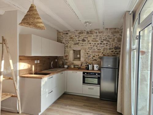een keuken met witte kasten en een zwarte koelkast bij La Vigne Blanche Gîtes in Lamotte-du-Rhône