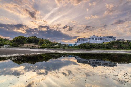 a building on the beach with a reflection in the water at Spa and Resort Hotel Solage Oita Hiji Beppuwan in Beppu