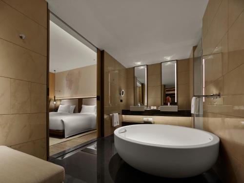 a bathroom with a tub and a bedroom with a bed at Angsana Zhuhai Hengqing in Zhuhai