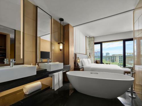 a bathroom with two sinks and a large bath tub at Angsana Zhuhai Hengqing in Zhuhai