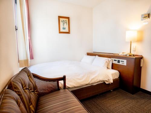小牧市にある小牧シティホテルのベッド1台とソファが備わる小さな客室です。