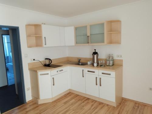 uma cozinha com armários brancos e pisos em madeira em Wohnung - zur Länd em Moosburg