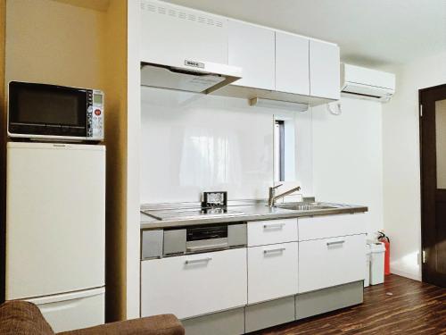 a white kitchen with a sink and a microwave at Tokyo Private villa/near station/Ginza/Asakusa/Sky Tree/Louis House in Tokyo