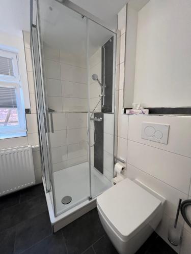 a white bathroom with a shower and a toilet at Altstadt Fewo Wernigerode in Wernigerode