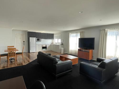 a living room with couches and a table and a kitchen at The Charles in Wagga Wagga
