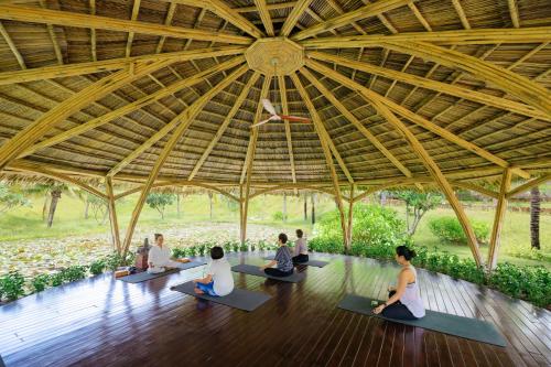 a group of people sitting in a yoga class in a pavilion at Fusion Resort Cam Ranh - All Spa Inclusive in Cam Ranh