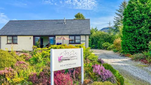 a house with a sign in front of it at Heatherbank Cottage in Onich