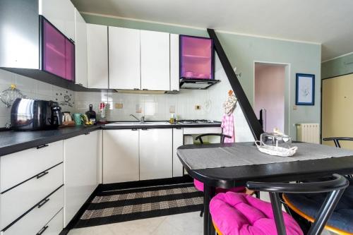A casa di Elga في تيرمولي: مطبخ مع دواليب بيضاء وطاولة مع كراسي وردية