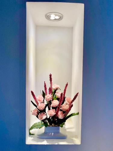 a vase with pink flowers in front of a mirror at De Vivre Homestay Măng Đen in Kon Von Kla