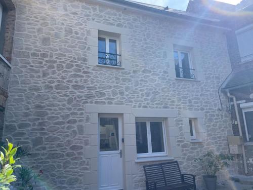 a stone house with a white door and windows at Au coeur du lin in Doudeville