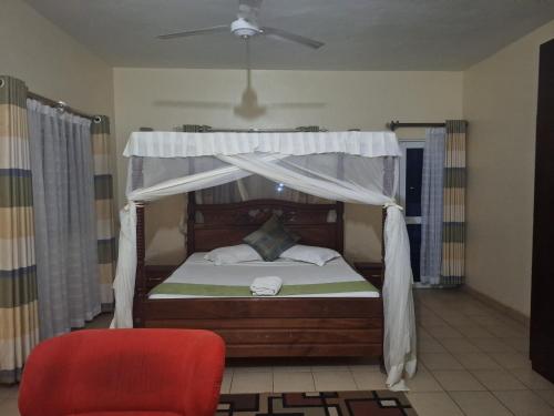 1 dormitorio con cama con dosel y silla roja en HomeAway_Luxurious Malindi en Malindi
