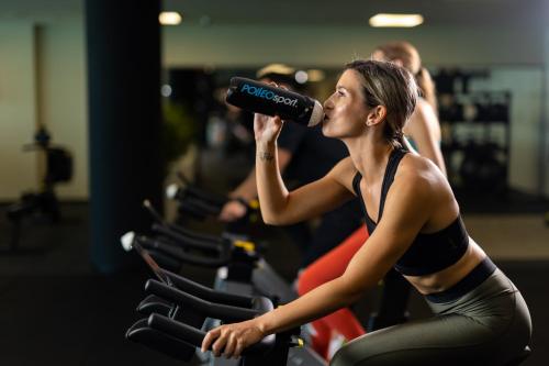 a woman drinking from a bottle in a gym at Hilton Rijeka Costabella Beach Resort And Spa in Rijeka