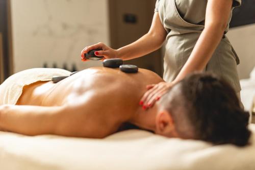 a woman is giving a man a massage at Hilton Rijeka Costabella Beach Resort And Spa in Rijeka