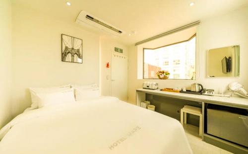 a white bedroom with a bed and a sink at Hotel MARE in Busan
