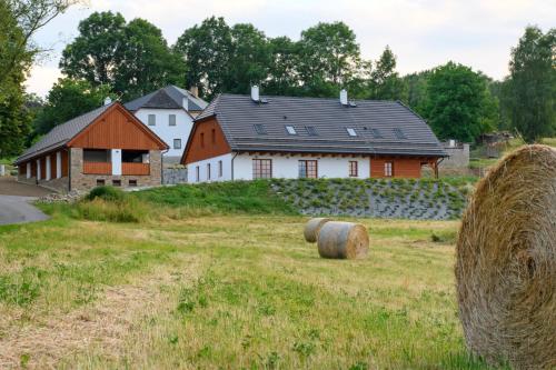 a field with hay bales in front of a house at Chalupa Pod Šerovnou 