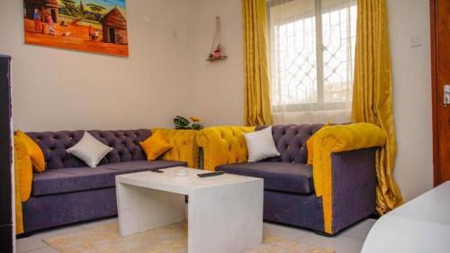 a living room with a purple couch and a table at Lux Suites JSB Apartments Bamburi in Bamburi