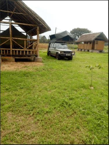 a car parked in a field next to a building at Ishasha Pride Lodge in Kihihi