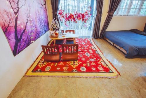 a living room with a red rug and a bed at De Vivre Homestay Măng Đen in Kon Von Kla