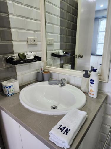 y baño con lavabo blanco y espejo. en Cozy and Spacious Condo Unit with Free Netflix en Manila