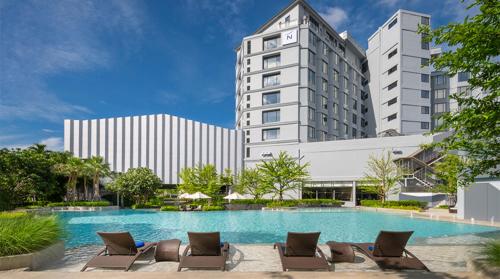 a hotel with a swimming pool and lounge chairs at Novotel Rayong Star Convention Centre in Rayong