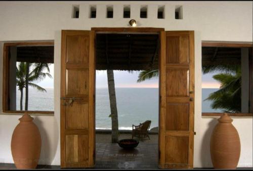 una puerta abierta a una habitación con vistas al océano en Karikkathi Beach Villa rooms en Thiruvananthapuram