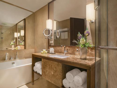 a bathroom with a sink and a tub and a mirror at Ascott Bonifacio Global City Manila in Manila